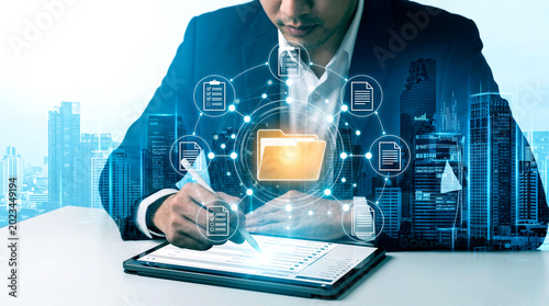 Digital document management system with businessman using tablet, double exposure of office buildings and cloud storage folder icon