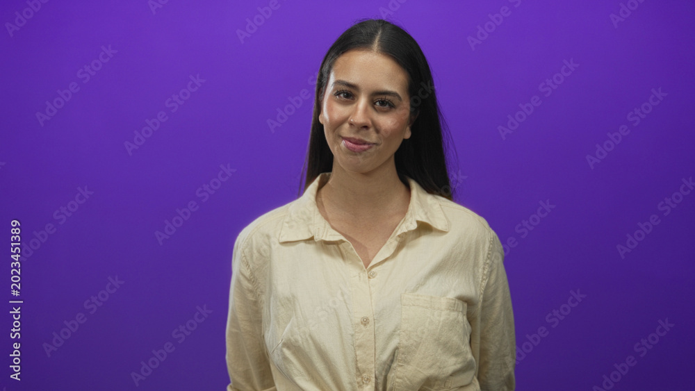 Fototapeta premium Woman brunette with head tilt and slight smile showing face and neck in studio with purple backdrop; confidence casual ease.