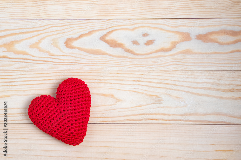 Obraz premium Red crochet heart on a light wooden background.