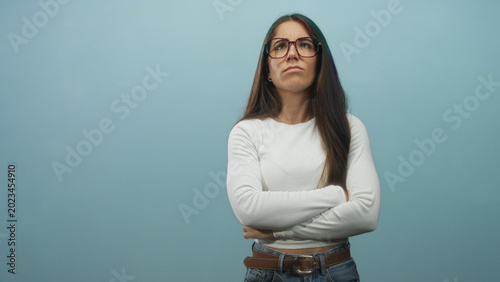 Photography Woman with glasses raises hands palms up in expressive gesture showing palms and crossed arms in later frames against a blue studio backdrop; frustration