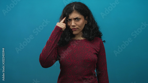 Foto Young brunette woman pointing finger at camera in teal studio with serious expression and direct gaze; anger defiance
