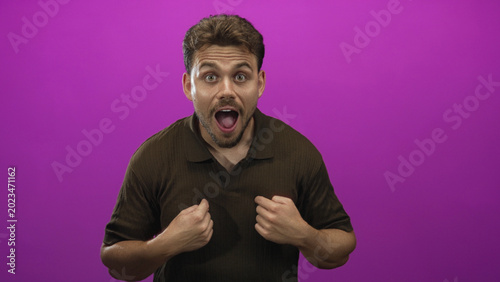 Schilderij op canvas Young hispanic man points fingers to chest and smiles broadly while gesturing in purple studio; enthusiasm confidence