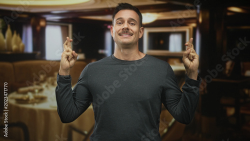 Konstfotografi Man with moustache pressing hands together in prayer at a restaurant table inside a building; hopeful plea
