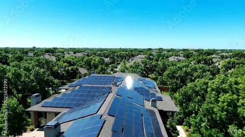 Modern solar panels on house roof surrounded by lush green trees
