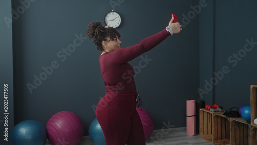 Foto Woman holding red smartphone aloft taking a selfie in a studio with yoga balls and dumbbells visible; confidence wellness