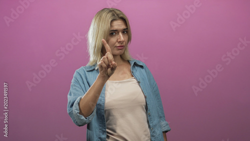 Foto Woman wearing denim shirt and beige camisole pointing index finger toward camera in studio; stern disapproval