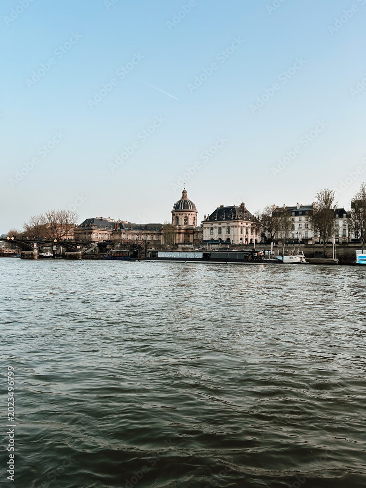 Obraz premium Seine River in Paris with historic architecture and Institut de France skyline, peaceful urban waterfront view with classic travel atmosphere