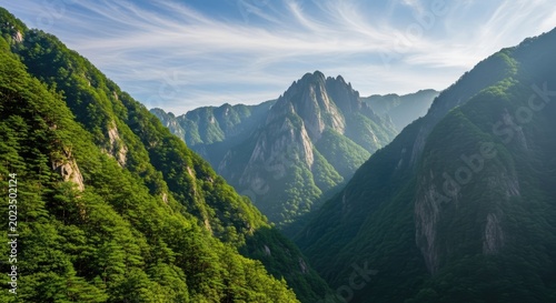 Majestic green mountain peaks and deep valley under blue sky