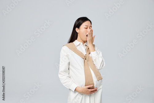 Fotografie Sleepy Pregnant Woman Yawning and Holding Belly