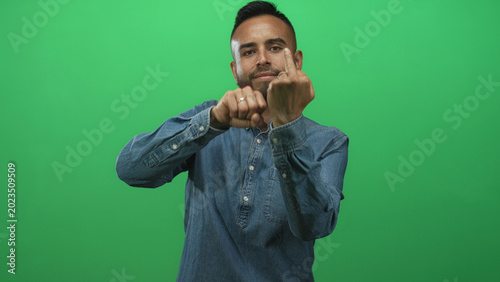Bild auf Leinwand Man showing fists and raised middle finger with visible hands in green studio; defiance attitude rebellion