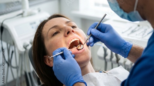 Woman receives dental check-up at clinic with dentist examining mouth during routine appointment
