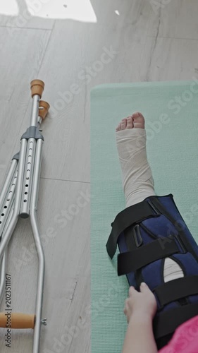 Woman wearing bandage onto a broken leg and ankle on the floor at home