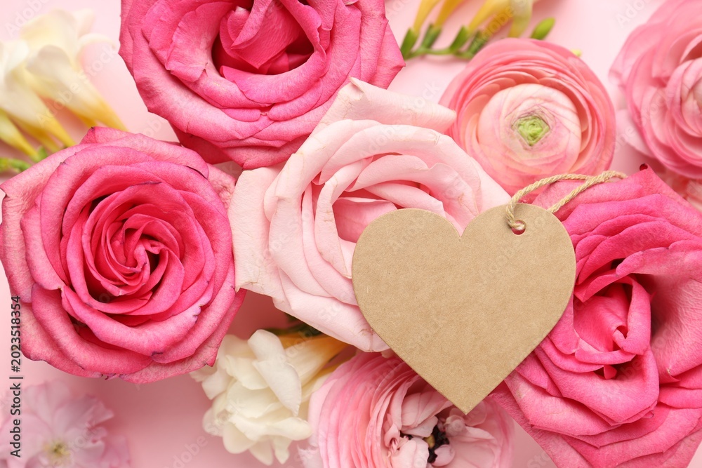Fototapeta premium Beautiful flowers and blank heart shaped card on pink background, top view. Space for text
