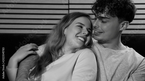 Happy young couple embracing on sofa black and white