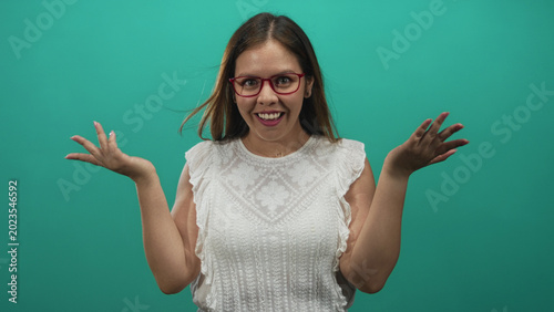 Foto Woman with red glasses pointing finger in studio against teal backdrop wearing white lace blouse, direct gesture; assertive challenge
