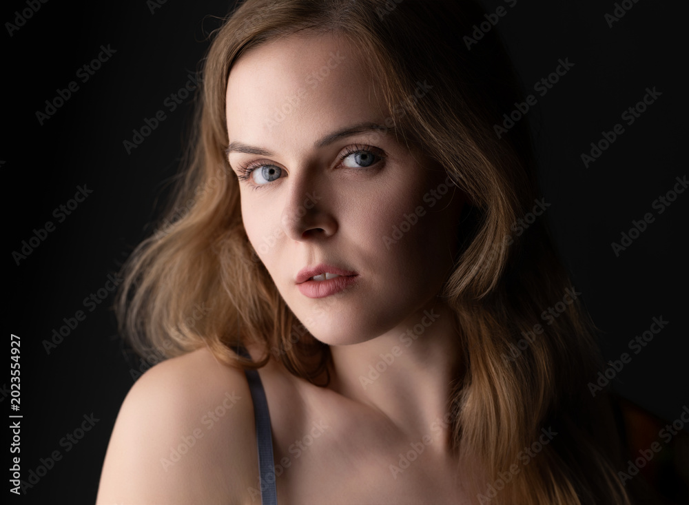 Fototapeta premium Young woman posing in a studio with soft lighting and a dark background
