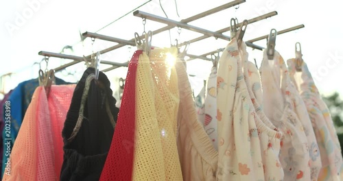 Baby clothes and fabric hanging in warm sunlight outdoors, capturing freshness, cleanliness, cozy family lifestyle, and natural morning light