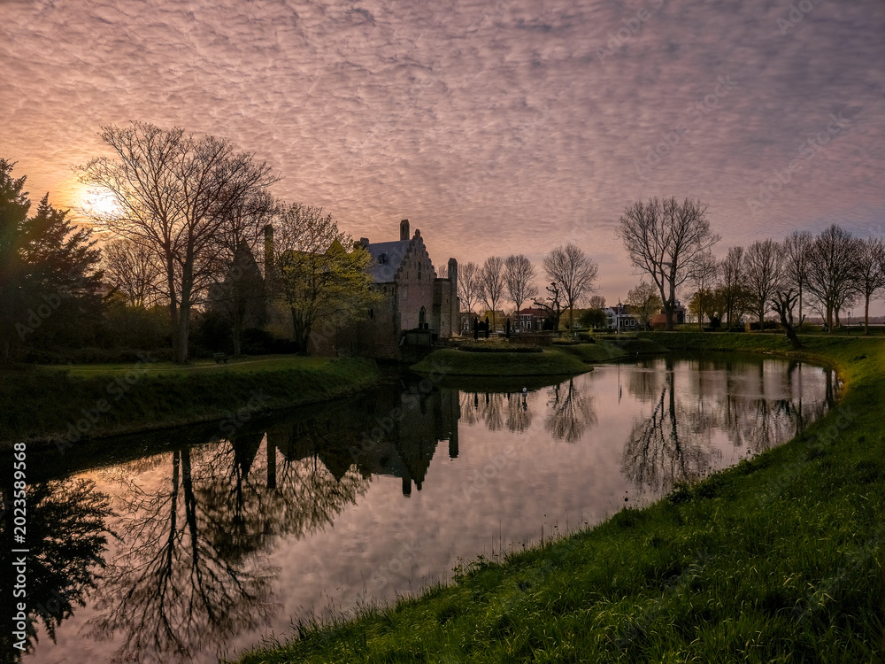 Fototapeta premium Kasteel Radboud Medemblik Netherlands — Atmospheric Sunset Castle Reflection in Moat Golden Light
