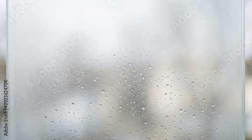 Tableau sur toile Water droplets on frosted glass pane with blurred natural background