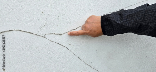 The construction worker pointed out large, rather deep crack in white plaster wall. Crack was diagonal or ran across wall, possibly warning sign of structural problem. Diagonal cracks at 45degree angl