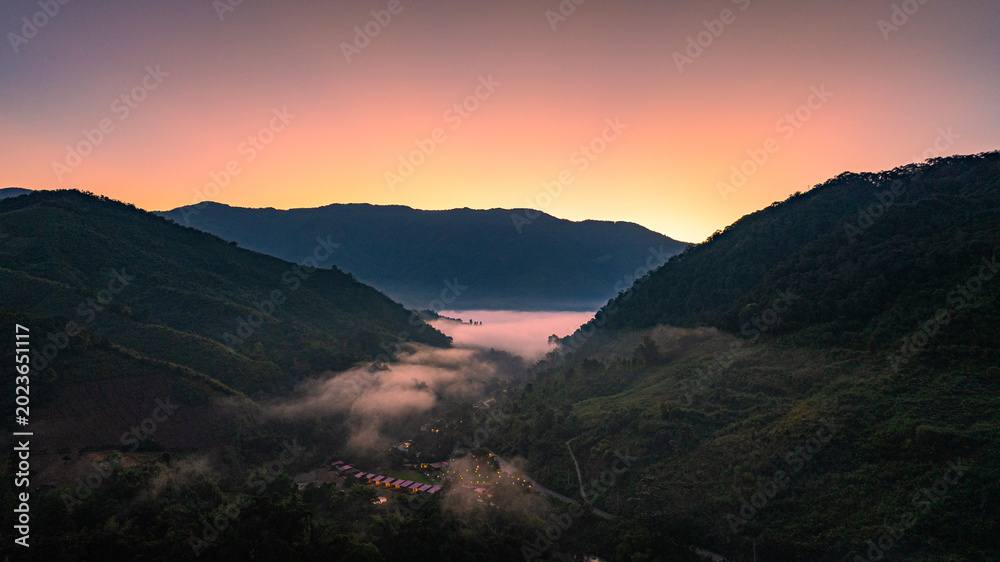 Naklejka premium A radiant sunrise slowly brightens the mountain horizon, revealing rolling ridges touched by warm golden light. The shifting colors and soft morning glow create a calm, breathtaking time lapse scene.
