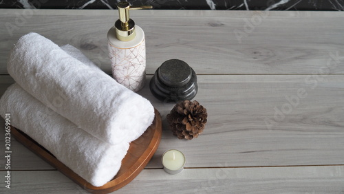 Canvas Print Luxury spa composition with soft rolled towels, candle, massage stones and skincare dispenser on elegant marble background