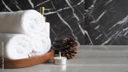 Photography Luxury spa composition with soft rolled towels, candle, massage stones and skincare dispenser on elegant marble background
