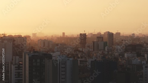 Golden sunset light illuminating the hazy city skyline of lima, peru with construction cranes