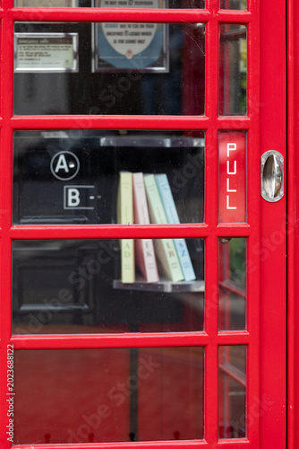 Foto Red telephone box with vintage phone and reprinted telephone directories