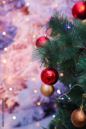 Elegant Christmas ornaments hanging on a glowing pine tree create a warm festive atmosphere with colorful lights, soft bokeh, and cozy holiday vibes perfect for seasonal backgrounds in wintertime. 4k.