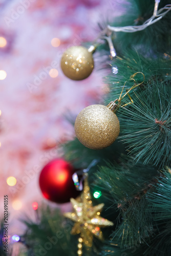 Elegant Christmas ornaments hanging on a glowing pine tree create a warm festive atmosphere with colorful lights, soft bokeh, and cozy holiday vibes perfect for seasonal backgrounds in wintertime. 4k.