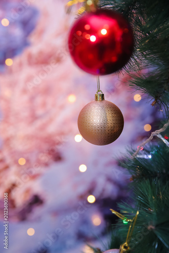 Elegant Christmas ornaments hanging on a glowing pine tree create a warm festive atmosphere with colorful lights, soft bokeh, and cozy holiday vibes perfect for seasonal backgrounds in wintertime. 4k.