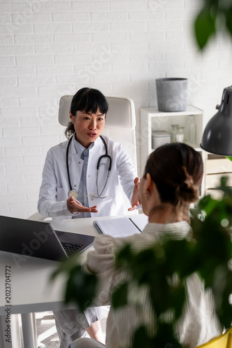 Female physician talking with patient during healthcare consultation in modern office. Medical advice, emotional support and preventive care concept.