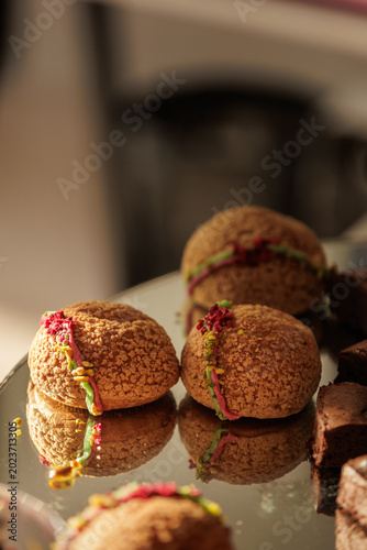 Εκτύπωση καμβά Close-up of delicate choux pastry puffs with pistachio and raspberry garnish on a reflective surface during an elegant catered event