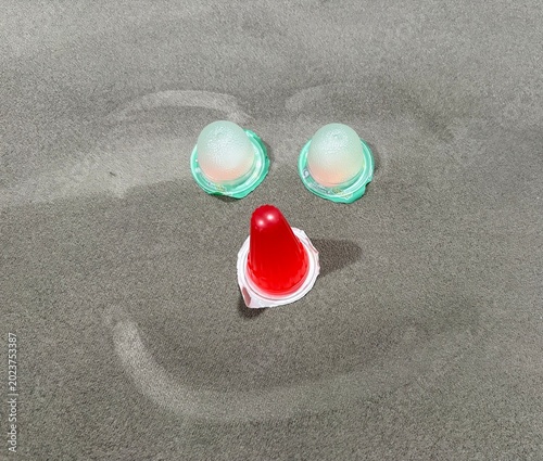 Creative smiley face arranged with colorful mini jelly cups on a grey surface, cheerful conceptual art using sweet gelatin snacks, top view.