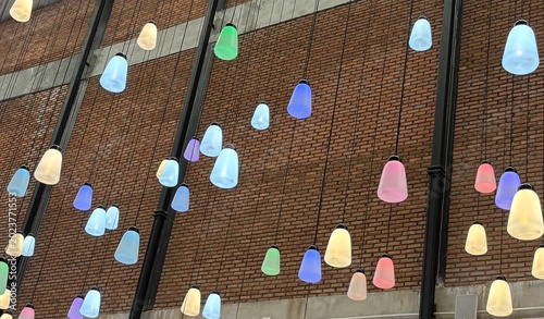 Modern colorful pendant hanging lamps illuminating against a brown brick wall background, vibrant decorative ceiling light fixtures for interior design.