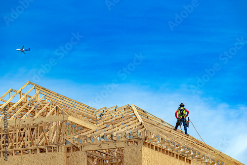 Foto Wide low-angle view of a construction worker standing on a wooden roof truss sys