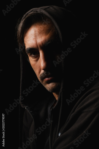 Foto Mysterious figure in dark hoodie gazes with intensity in shadowy setting