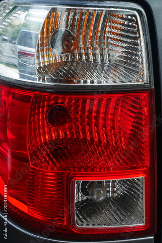 Close up of a modern car tail light assembly with red and clear caps, showing brake light and turn signal details.