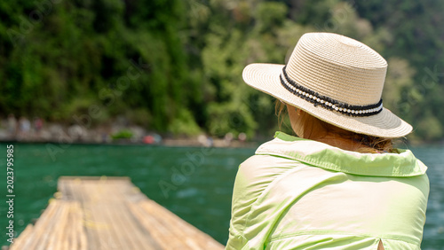 Fotografie Woman gazes at calm lake from wooden dock
