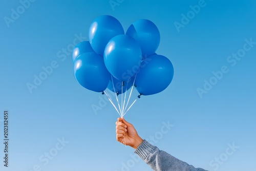 Father holds blue helium balloons to celebrate the birth of a boy