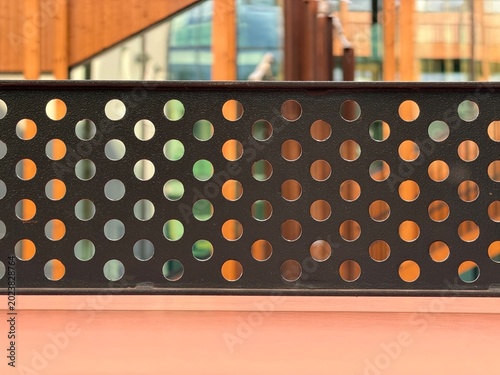 Perforated metal panel background with modern architecture blur