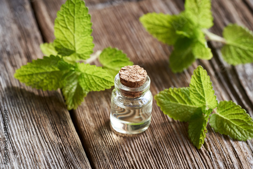 Foto Aromatherapy essential oil in a glass bottle with fresh melissa leaves