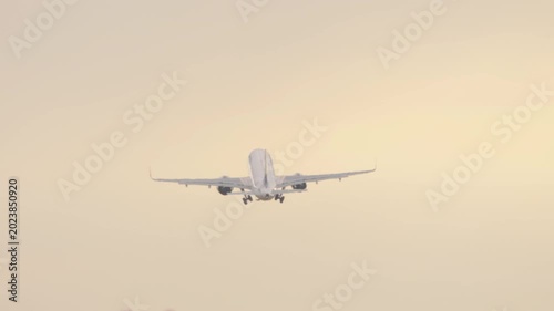 Jet aircraft taking off and climbing after departure from Almaty Airport during early morning sunrise light.