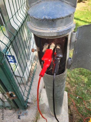 Foto Cathodic protection test station for underground natural gas pipeline, electrical potential measurement with red and black alligator clips