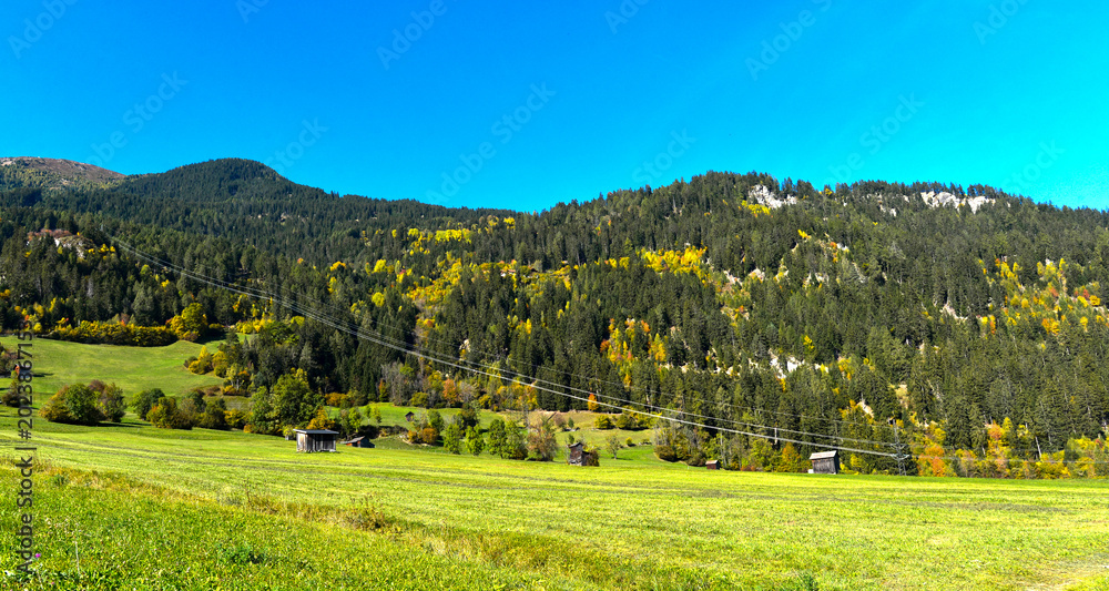 Obraz premium Herbstliche Bergwiesen mit traditionellen Heustadeln bei Prutz im Tiroler Oberinntal