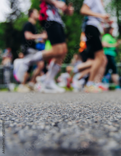 Marathon runners crowd, sportsmen participants start running the half-marathon in the city streets, crowd of sportswomen joggers in motion, group of athletes outdoor training competition in summer day