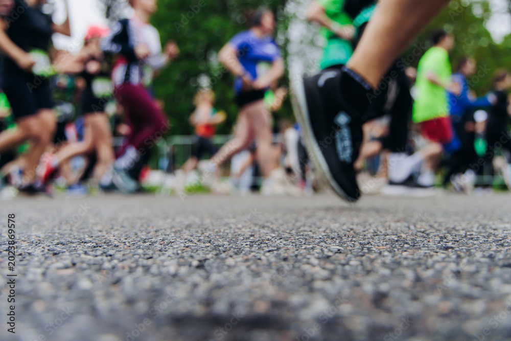 Fototapeta premium Marathon runners crowd, sportsmen participants start running the half-marathon in the city streets, crowd of sportswomen joggers in motion, group of athletes outdoor training competition in summer day