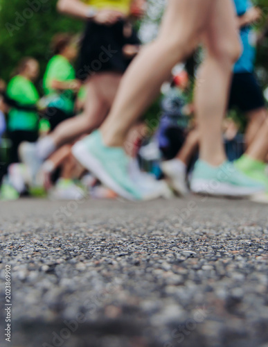 Marathon runners crowd, sportsmen participants start running the half-marathon in the city streets, crowd of sportswomen joggers in motion, group of athletes outdoor training competition in summer day