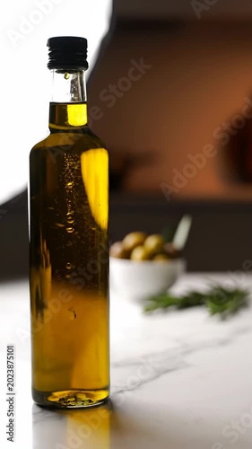 Olive oil bottle on marble counter with herbs